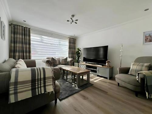 a living room with two couches and a flat screen tv at Dunmuir House 4 Bedroom 2 bathroom House & Garden in Denny in Falkirk