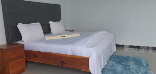 a bed with white sheets and a wooden head board at NEBCON Executive Lodge in Kitwe
