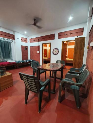 a room with a table and chairs and a couch at Kamoga Homestay in Virajpet