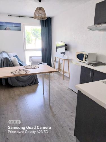 un salon avec une table et une cuisine dans l'établissement Studio avec piscine et parking gruissan, à Gruissan