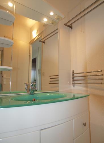 une salle de bain avec un lavabo vert et un miroir dans l'établissement Le Front de Mer, à Palavas-les-Flots