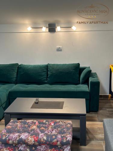 a living room with a green couch and a coffee table at Apartmani Kovačević MKM Banja Vrujci in Gunjica