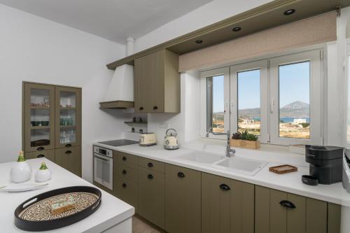 a kitchen with a sink and a counter with windows at Naias View Home Milos in Adamantas
