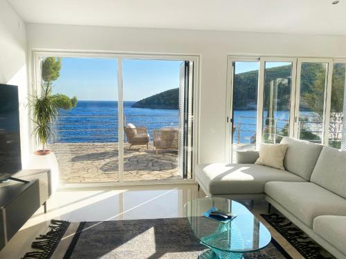 a living room with a couch and a view of the water at Villa Moro: Beachfront Privacy in Trstenik