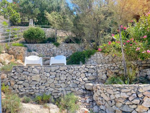 a stone wall with two chairs and a stone fence at Villa Moro: Beachfront Privacy in Trstenik
