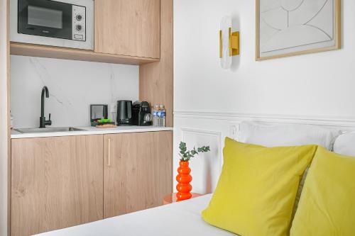 a bed with a yellow pillow and a microwave at JIJI Suites in Combs-la-Ville