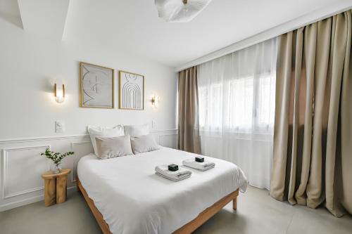 a white bedroom with a large white bed and a window at JIJI Suites in Combs-la-Ville