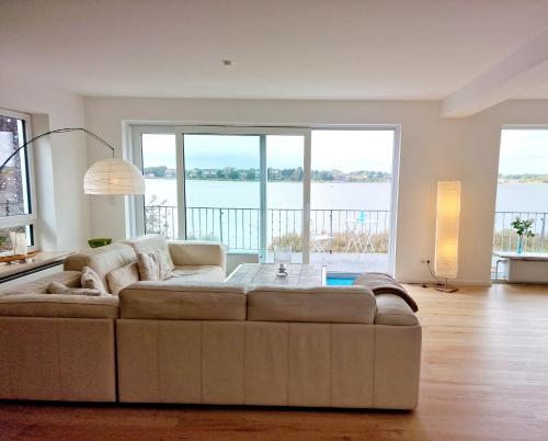 a living room with a couch and large windows at Fjordhaus Schleiwind in Fahrdorf