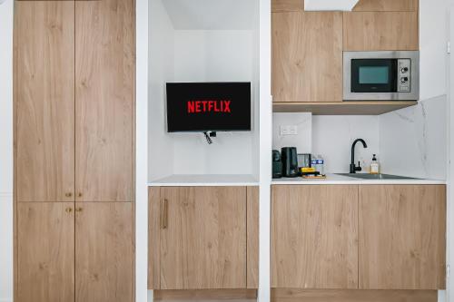 a wooden cabinet with a microwave and a kitchen at JIJI Suites in Combs-la-Ville