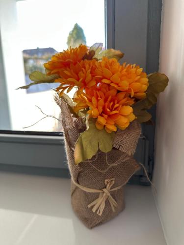 a vase of orange flowers sitting on a window sill at Moderne FerienWohnung NeuBau Merzig in Merzig