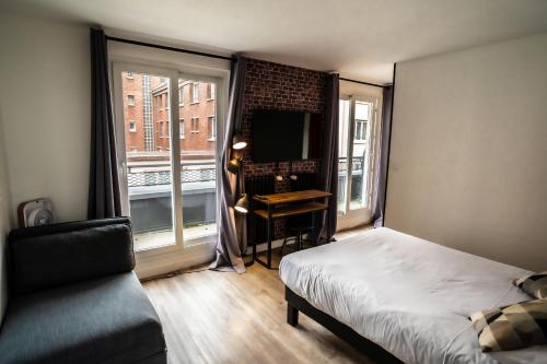 a bedroom with a bed and a desk and a window at Hotel De Quebec in Rouen
