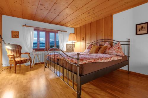 a bedroom with a bed and a chair and a window at Sérénité Spiez, Lakeview, Chalet in Einigen