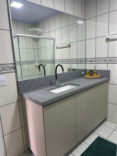 a bathroom with a sink and a mirror at La Vita hospedaria studio verde in Nova Veneza