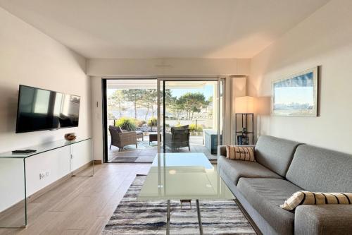 un salon avec un canapé et une télévision dans l'établissement Appartement les pieds dans l'eau - T2 de standing, à Guidel