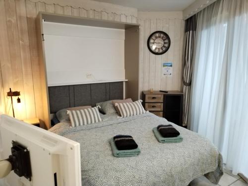 Un dormitorio con dos camas y un reloj en la pared. en Studio les Pieds dans L'eau au bord du lac d'Annecy, en Duingt