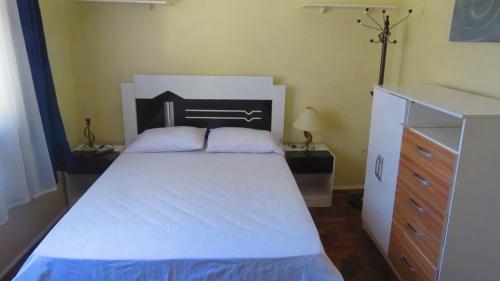 a bedroom with a white bed and a dresser at Apt térreo Gonçalves Chaves prox Bento in Pelotas