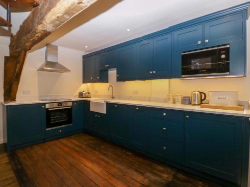 a kitchen with blue cabinets and a wooden floor at The Old Cider Press in Broadway