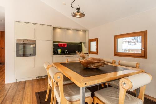 a kitchen and dining room with a wooden table and chairs at Sonnmatten Boutique Hotel & Apartments Zermatt in Zermatt