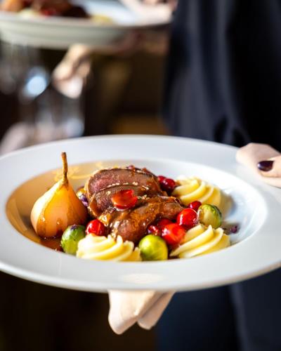 a person holding a plate of food with meat and vegetables at Hotel Restaurant Het Witte Paard in Delden