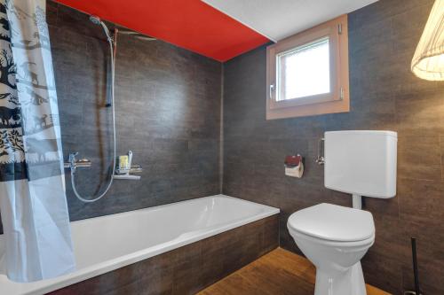 a bathroom with a tub and a toilet and a shower at Sérénité Spiez, Lakeview, Chalet in Einigen