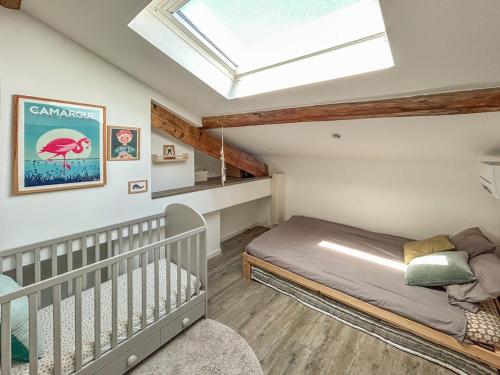 - une petite chambre avec un lit bébé et une lucarne dans l'établissement Parc Clemenceau - centre historique, à Montpellier
