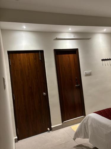 two wooden doors in a room with a bed at PS Elite Homestay in Tirupati