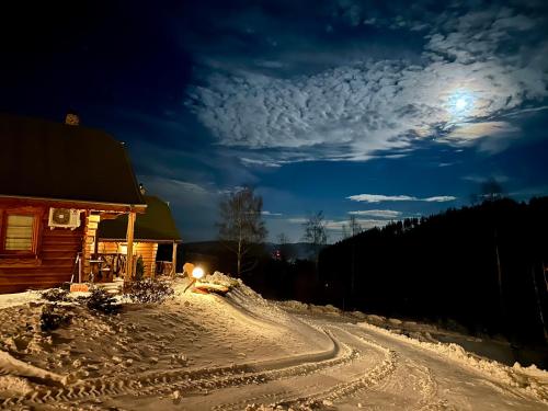 a snow covered road next to a cabin at night at Domki w górach '' Zielone Wzgórza '' okolice Karpacza in Karpacz