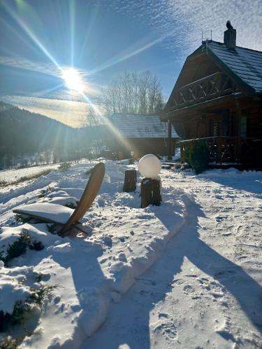 a snow covered yard with a house and the sun at Domki w górach '' Zielone Wzgórza '' okolice Karpacza in Karpacz