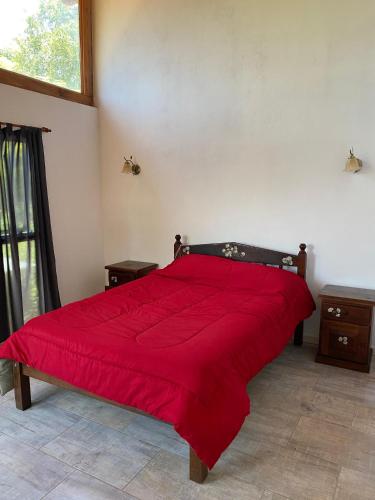 a bedroom with a red bed with a red comforter at Cabaña Rubí, Complejo El Colibrí in Villa del Dique