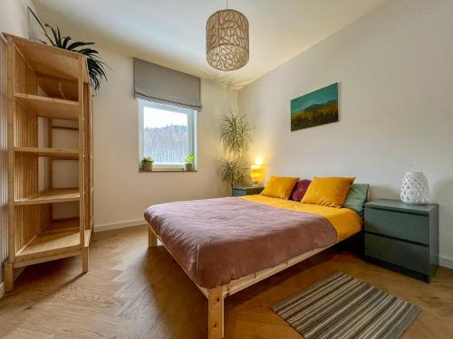 a bedroom with a bed with yellow sheets and a window at W centrum uzdrowiska in Jedlina-Zdrój