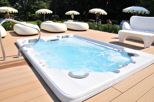 a hot tub on a deck with chairs and umbrellas at Park Hotel Villa Giustinian in Mirano