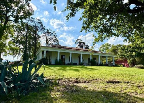 une maison blanche avec une grande pelouse devant dans l'établissement Estancia Pozo de Correa, à Agua de las Piedras