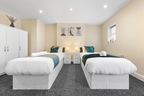 two beds in a bedroom with white walls at Spacious London 2-Bed Flat with a King Bed-Save on Long Stays-5 Separate Beds- Parking Available! in Barnet