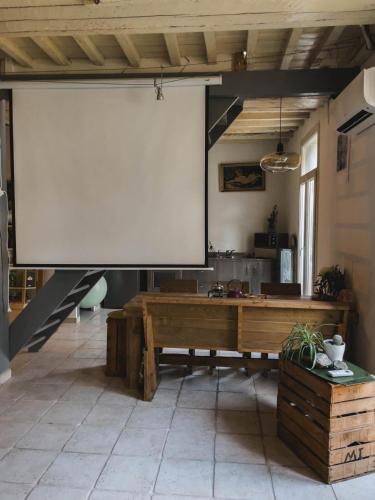 un grand écran de projection blanc dans une pièce avec une table dans l'établissement O Saudade - Centre Perpignan, à Perpignan
