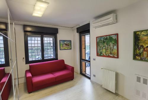a living room with a red couch and windows at Ballarin Studio Apartment for Business Travels and Holidays in Rome