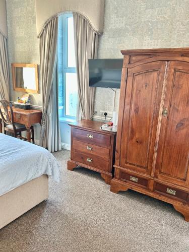 a bedroom with a wooden dresser and a large wooden cabinet at Albany Lodge in Portrush