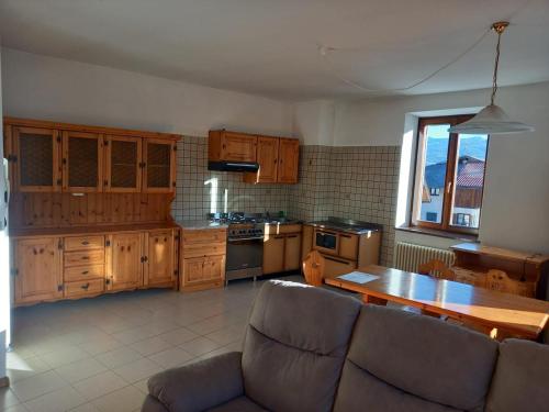 a kitchen with wooden cabinets and a table and a couch at Brenta Casa Vacanze - Apartments in Cunevo