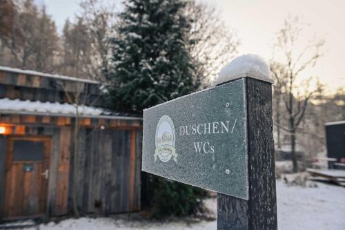 a sign in the snow in front of a cabin at Green Tiny Village Harz - Sleep Space 32 in Osterode