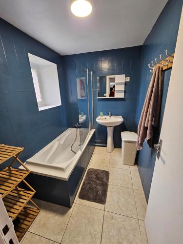 La salle de bains bleue est pourvue d'une baignoire et d'un lavabo. dans l'établissement Jolie Longère Bretonne, à Fréhel