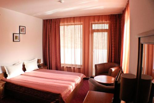 a hotel room with a bed and a chair at Hotel Bozhentsi in Chernevtsi