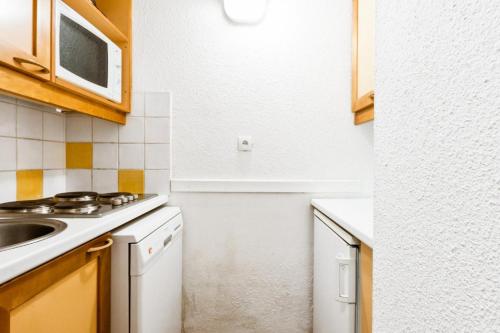 une cuisine avec un évier et une cuisinière four supérieur dans l'établissement Résidence Le Hameau du Sauget - maeva Home - 2 Pièces 4 Personnes Confort MAE-8461, à La Plagne Tarentaise