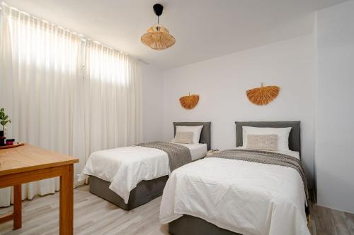 zwei Betten in einem Schlafzimmer mit weißen Wänden in der Unterkunft Villa isola plaka Naxos in Plaka