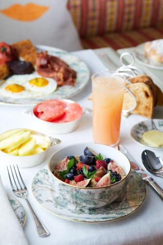 a table with plates of breakfast food and a bowl of fruit at Warren Street Hotel in New York