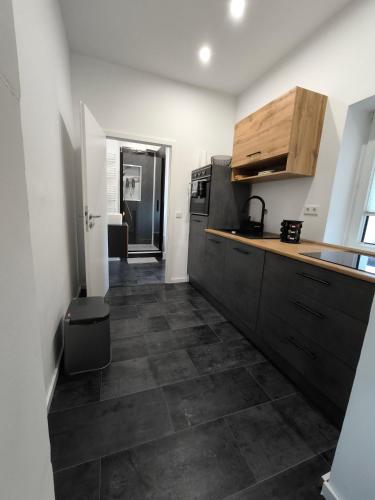 a kitchen with black cabinets and a tile floor at Villa Baumhaus Apartments in Hamm