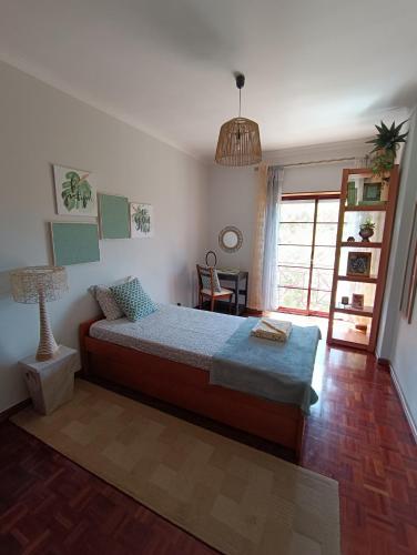 a bedroom with a bed and a table and a window at GREEN GARDEN APARTMENT IN ODIVELAS in Odivelas