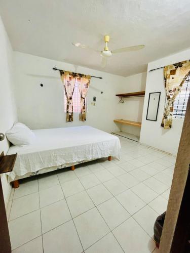 a bedroom with a bed and two windows at La casita in Tizimín