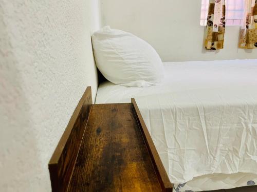 a bed with a white pillow and a wooden foot board at La casita in Tizimín