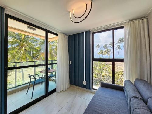 a living room with a couch and a view of the ocean at Flat pé na areia na praia de Porto de Galinhas próximo as piscinas naturais. in Porto De Galinhas
