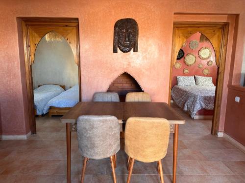 a dining room with a table and two beds at The Mogador's Oasis in Akermoud