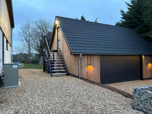 a garage with a staircase leading up to it at The Cartlodge - Studio Loft Apartment in Horringer, Bury St Edmunds in Westley